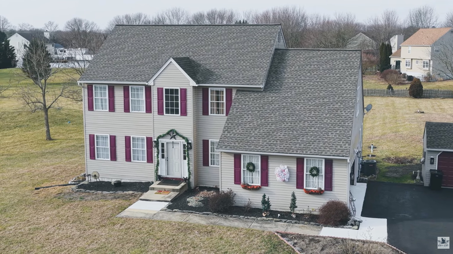 Aerial view of a two-story colonial home listing with driveway and yard