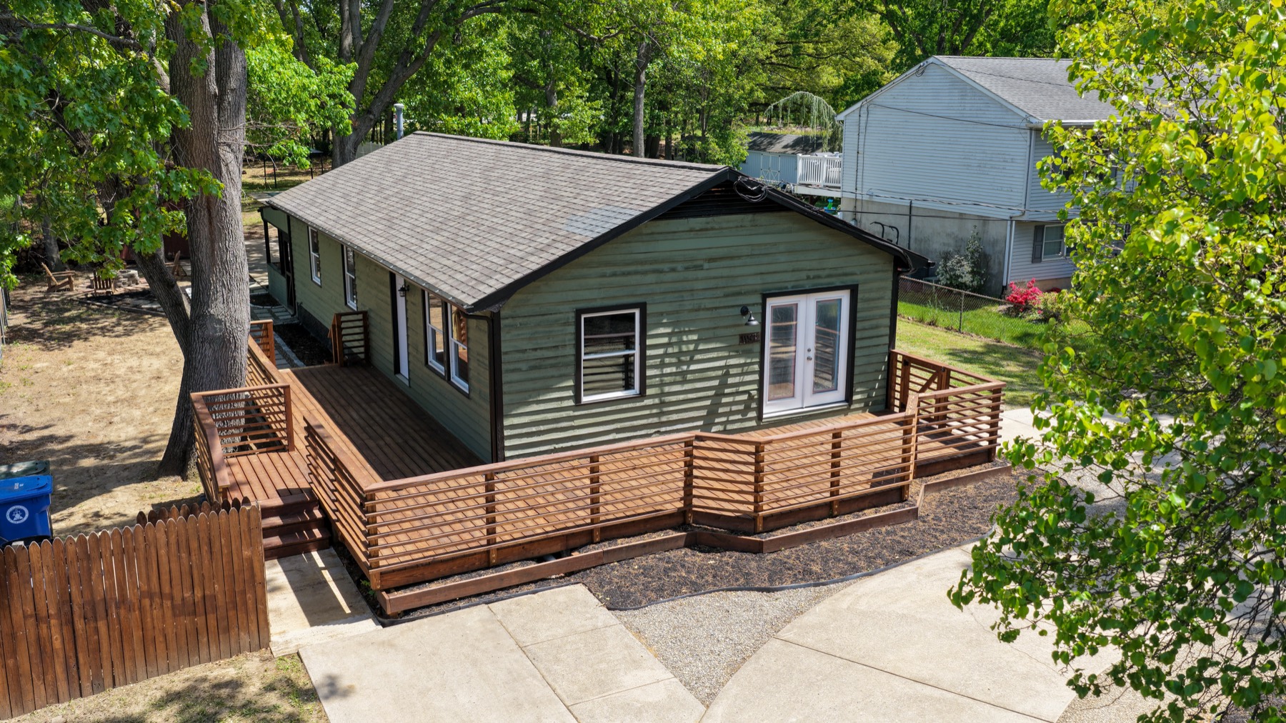 Close aerial detail of a finished wraparound deck and railing on a remodeled house
